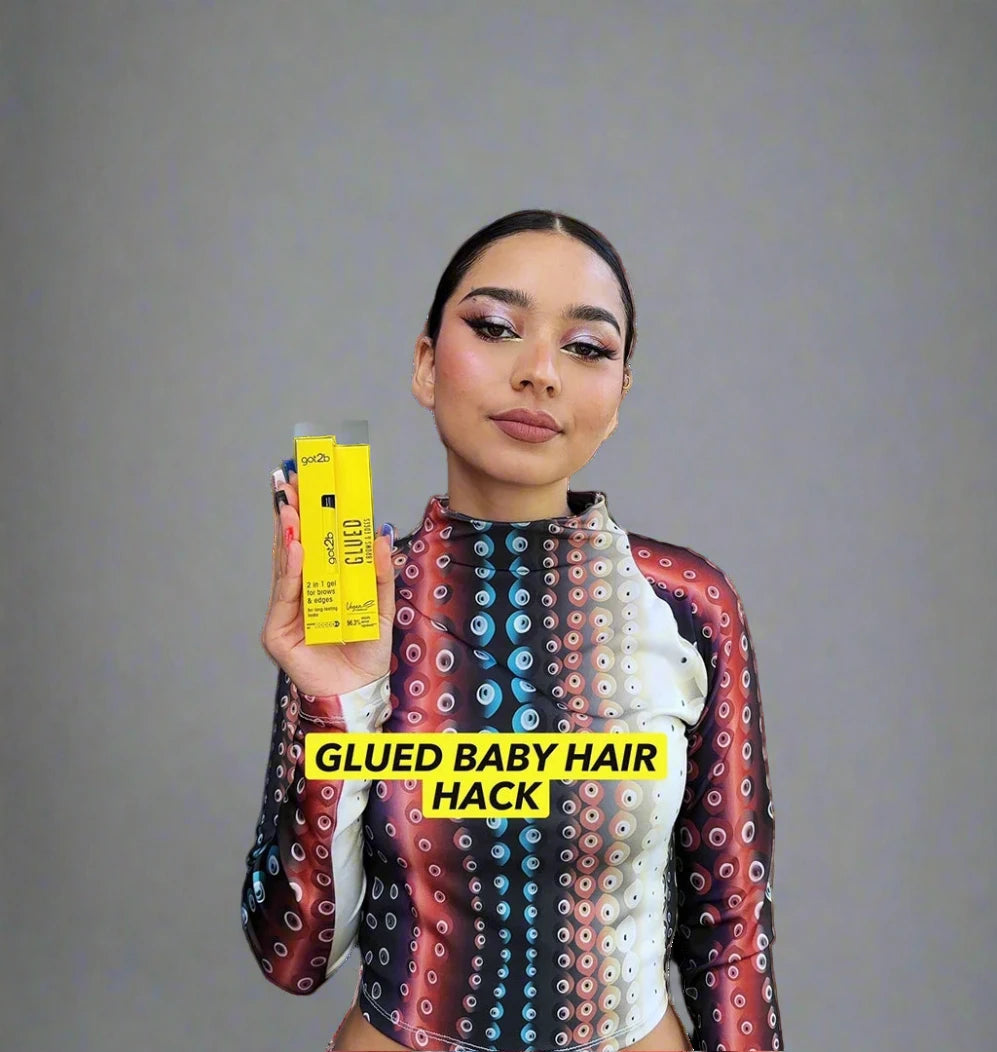 Woman holding a yellow product box with text 'GLUED BABY HAIR HACK' against a textured wall.